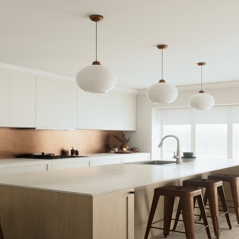 Îlot central en bois clair et comptoir blanc dans une cuisine moderne. Éclatante crédence cuivre, suspensions globe et tabourets bronze.